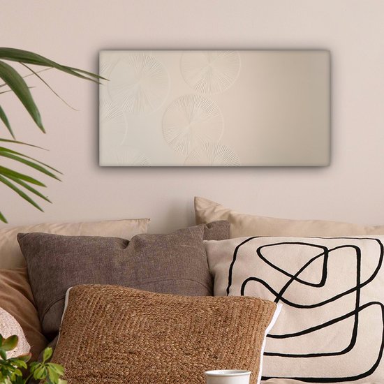 Beige canvas met cirkelvormige patronen, hangend boven een bank met diverse sierkussens.