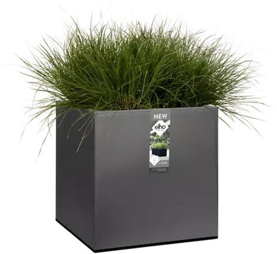 Een vierkante, grijze plantenbak gevuld met lang, groen gras en een Elho label.
