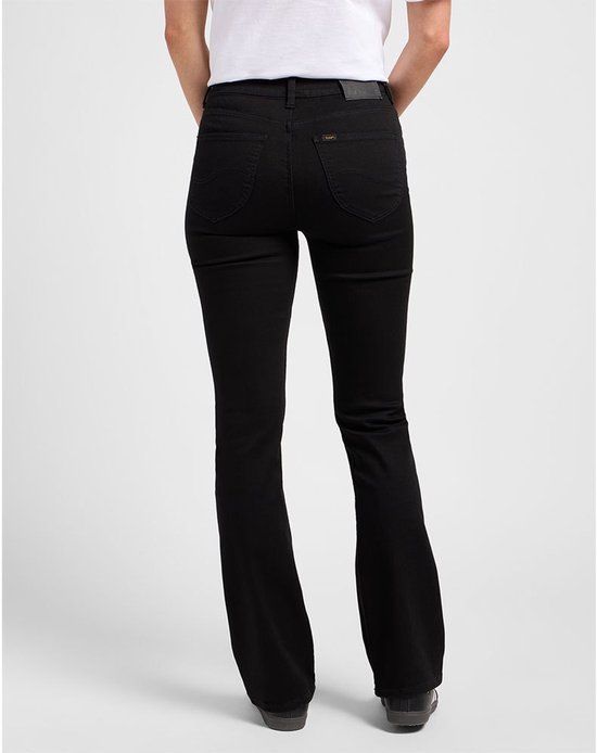 Model van achteren gezien in zwarte flared jeans met een wit T-shirt en donkere sneakers.