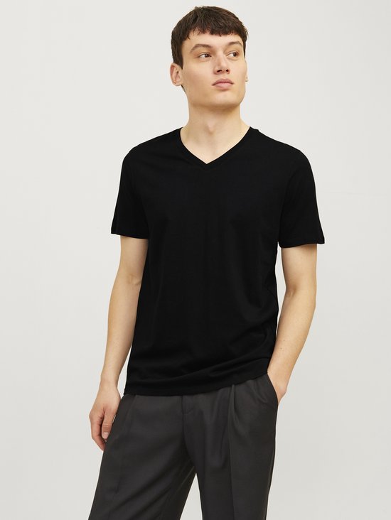 Man met zwarte T-shirt met V-hals en grijs pinstreep broek.