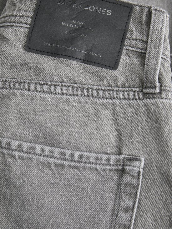 Detail van de achterkant van een grijze spijkerbroek met merkpatch en zak.