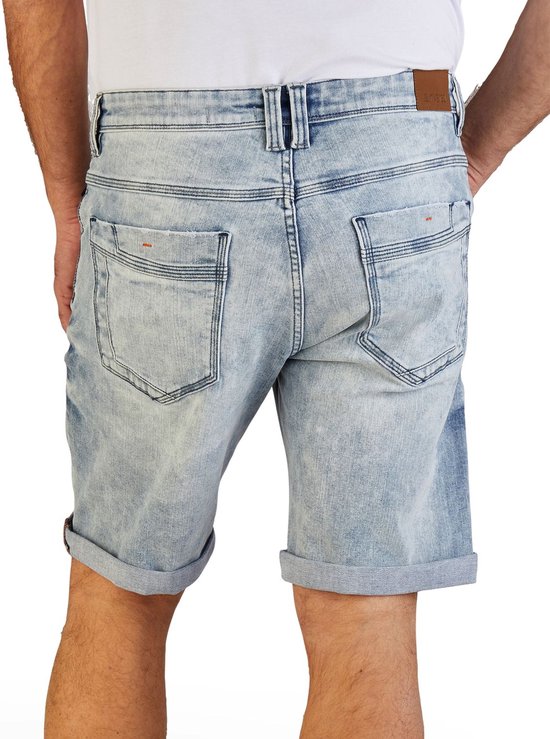Achterkant van een man in een lichtblauwe korte spijkerbroek met omgeslagen pijpen.