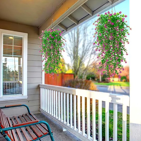 Twee hangende planten met roze bloemen en groene bladeren, boven een veranda met bankje en witte balustrade.