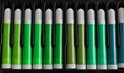 Een reeks groene stiften met witte dopjes, geordend in een zwarte doos.