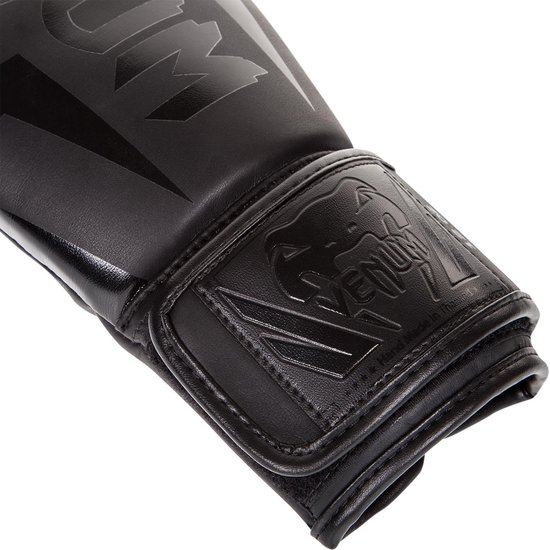 Detail van de polsband van een zwarte Venum bokshandschoen met reliëf logo en 'Hand Made in Thailand' tekst.