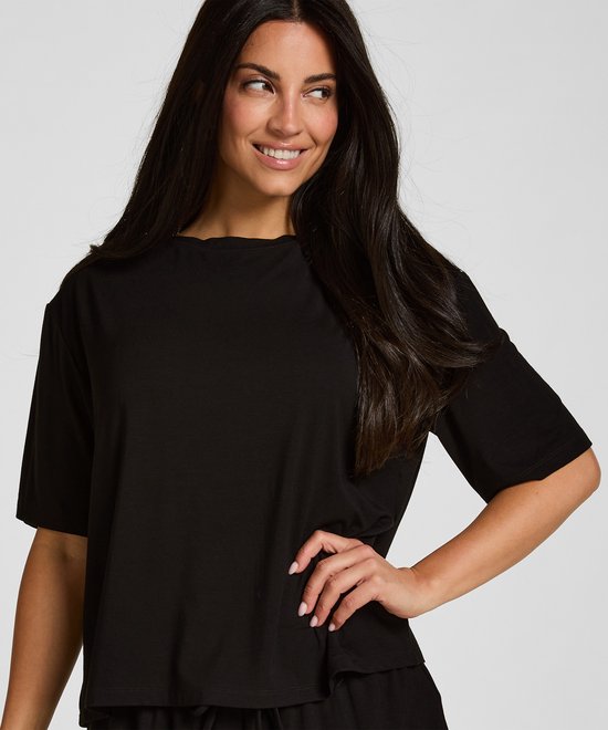 Close-up van model in een zwart pyjamashirt met korte mouwen.