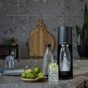 Zwarte SodaStream Terra met bruisende fles, glas met limoen en munt, en een zebra beeldje.