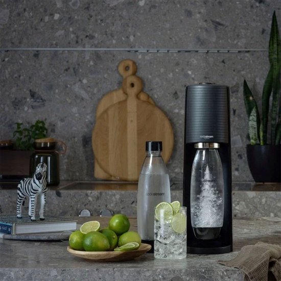 Zwarte SodaStream Terra met bruisende fles, glas met limoen en munt, en een zebra beeldje.