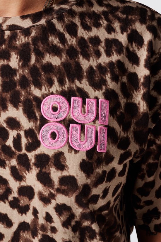 Close-up van roze 'OUI OUI' borduursel op een bruin t-shirt met dierenprint.