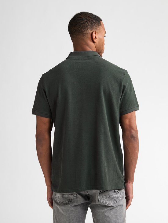 Man, van achteren gezien, draagt donkergroen poloshirt met korte mouwen en grijze jeans.