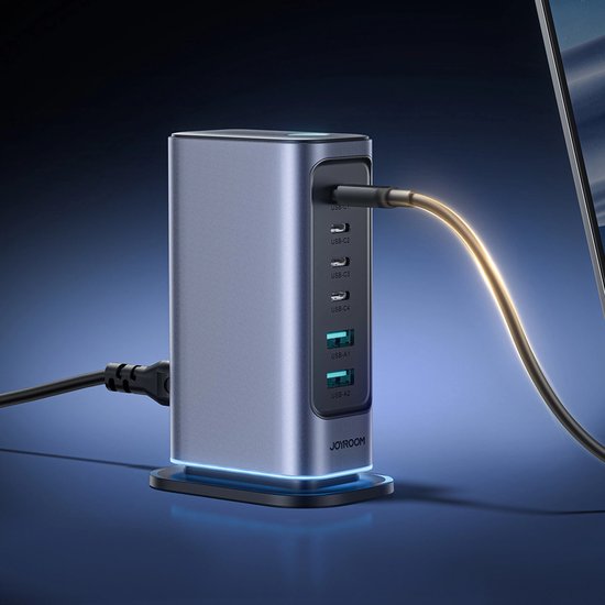 Grijze Joyroom 65W oplader met 4 USB-C en 2 USB-A poorten, aangesloten op een laptop met een gouden kabel.