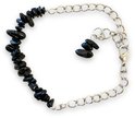 Zilverkleurig schakelarmbandje met ruwe zwarte steentjes en een klein extra steentje als sluiting.