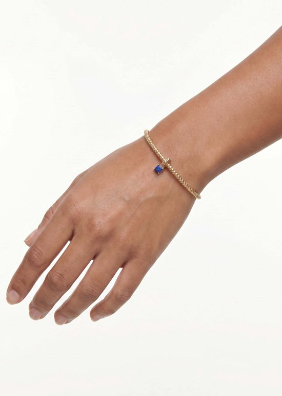 Hand met een gouden armband met een blauwe lapis lazuli steen.