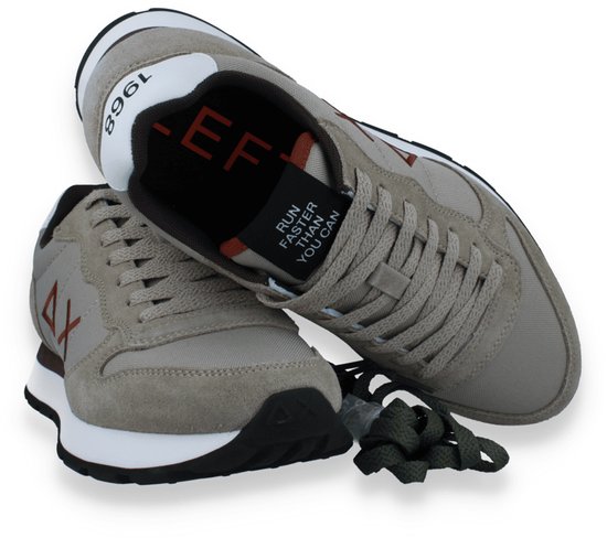 Twee beige sneakers, één met witte accenten en een bruine 'AX' logo. De tekst 'RUN FASTER THAN YOU CAN' is zichtbaar op de tong.