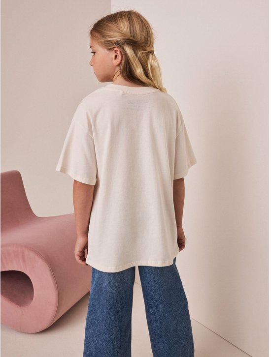 Crème oversized T-shirt met Minecraft print, gedragen door een meisje dat naar de achterkant kijkt.