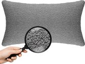 Lichtgrijze nekkussen in teddy bouclé stof, met vergrootglas dat de textuur toont.