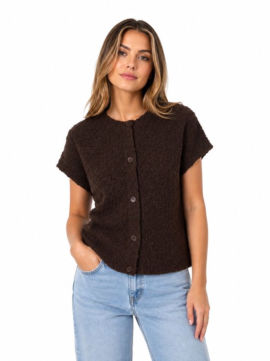 Bruine gebreide kortgerokte blouse met knopen en ronde hals. Het model draagt een lichte spijkerbroek.