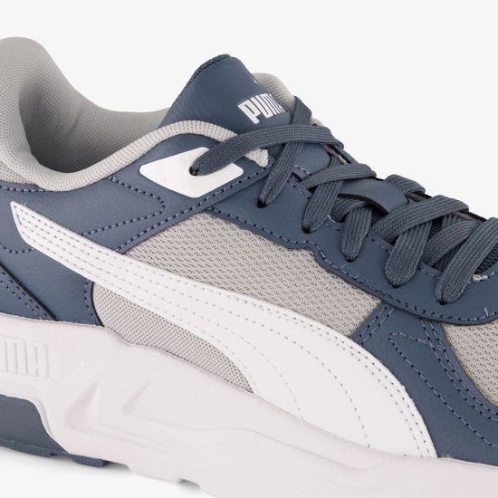 Close-up van de Puma sneaker met witte en grijze stof, met blauwe veters.