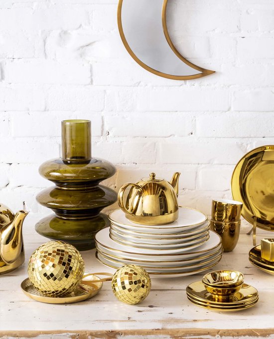 Gouden theepot en bijpassende suikerpot op een stapel witte borden met gouden rand. Gouden schaaltjes en decoratieve bollen ernaast.