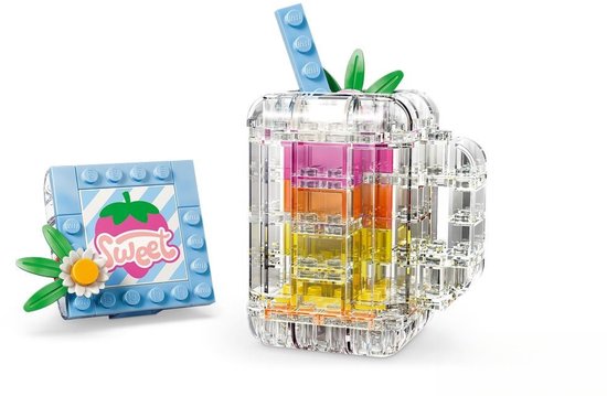 Verre transparent avec couches colorées, paille et feuille verte, à côté d'un bloc bleu clair avec imprimé fraise et texte 'Sweet'.