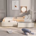 Wit bed met gecapitonneerd hoofdbord en lades, met beddengoed en decoratie.