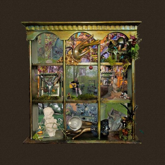 Diorama met antieke decoraties: een man met gitaar, schedels, engeltjes en een gouden hand.