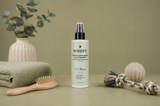 WØØFY Hydrate Detangling Leave-In Spray met lavendel voor honden, naast een handdoek, borstel en decoratie.