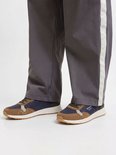Donkerblauwe en bruine Jack & Jones sneakers met witte zolen, gedragen met een grijze broek met witte streep.