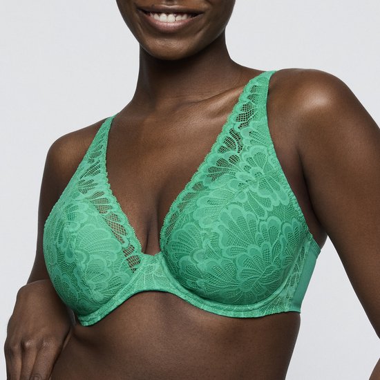 Model draagt een groene kanten bh met bloemenpatroon en diep decolleté.