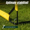 Close-up van de bevestiging van een geel Umbro voetbaldoeltje in gras, met grondpennen.