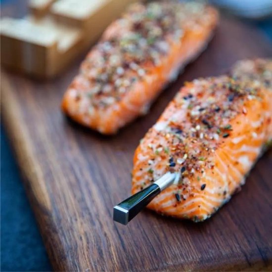 Meater+ thermometer in gegrilde zalmfilet op houten plank.