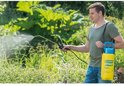 Man in groene polo spuit met gele Gloria Prima 5 drukspuit met blauwe handgreep in de tuin.