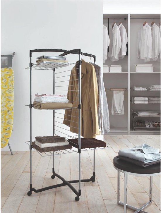 Zilverkleurige droogtoren met 3 etages, versierd met kleding en boeken, op wielen, naast een kast.