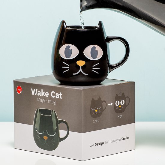 Tasse noire 'Wake Cat' sur boîte; de l'eau est versée, la tasse montre des yeux ouverts.