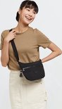 Model draagt een zwarte Kipling tas als heuptas. Ze draagt een bruin shirt en een beige rok.