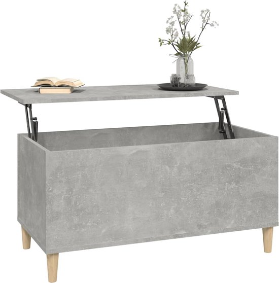 Betongrijze salontafel met het blad deels omhoog, met boeken en vaas.