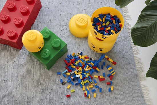 Lego opbergdozen in geel en groen, een rode Lego-bak, losse Lego-blokjes en een groene plant.