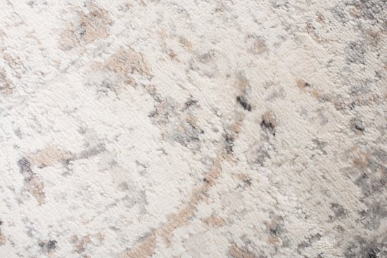 Gros plan de la matière douce d'un tapis vintage beige clair avec des accents gris et marron.