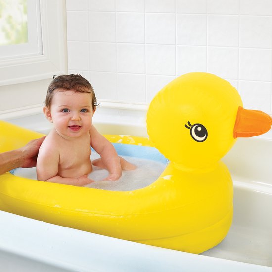 Vrolijke baby in een geel opblaasbaar badeendje badje in een badkuip.