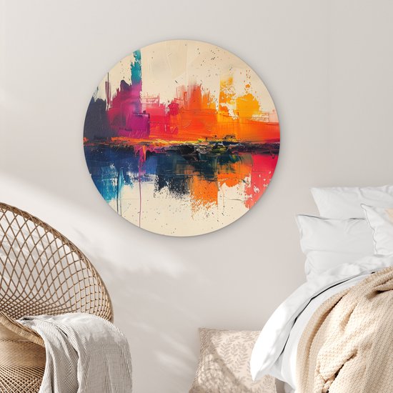 Abstracte muurcirkel met felle kleuren naast een rotan stoel en een bed.