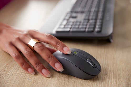 Vrouwenhand met gouden ring gebruikt een donkergrijze Logitech muis.