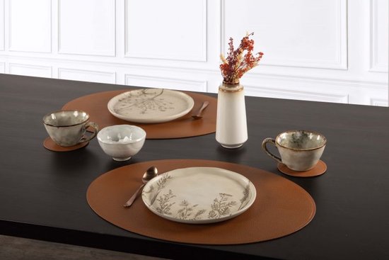 Sets de table ovales marron avec vaisselle beige et fleurs séchées marron sur une table.