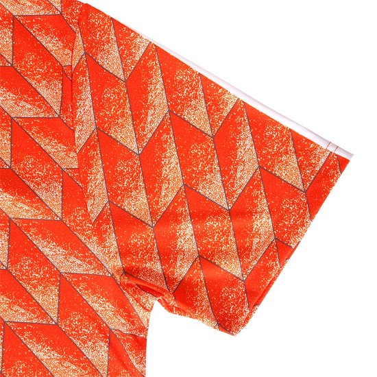Gedetailleerde opname van de mouw van een oranje voetbalshirt met geometrisch patroon.
