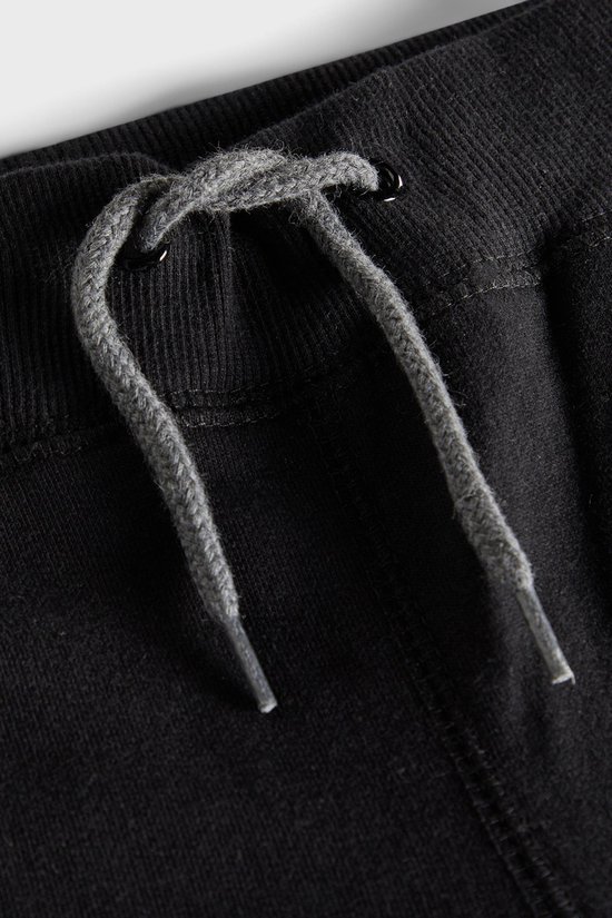 Detail van de tailleband van een zwarte joggingbroek met grijze veter