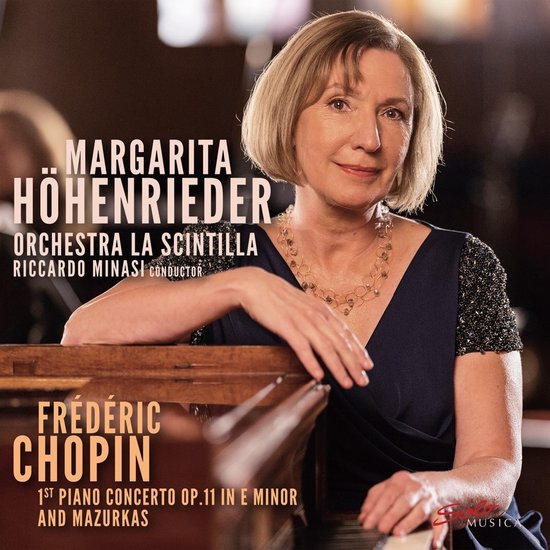 Margarita Hohnrieder, dirigente, met glinsterende ketting, leunend op een vleugel, Frédéric Chopin 1st Piano Concerto op.11 in E minor.