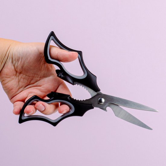 Hand houdt zwarte keukenschaar met vleermuisvormige handvatten vast.