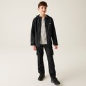 Jongen in zwarte waterdichte jas met capuchon, grijs T-shirt en zwarte cargo broek.