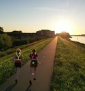 Twee vrouwen hardlopend bij zonsondergang, beiden dragen een geel reflecterend hardloopvest met LED-verlichting.