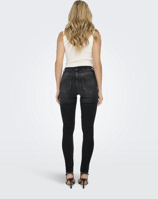 Model met blond haar draagt een strakke zwarte jeans van achteren gezien met een witte top.