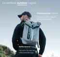 Man met grijze ONYX rolrugzak buiten, met reflecterend logo en waterbestendig materiaal.
